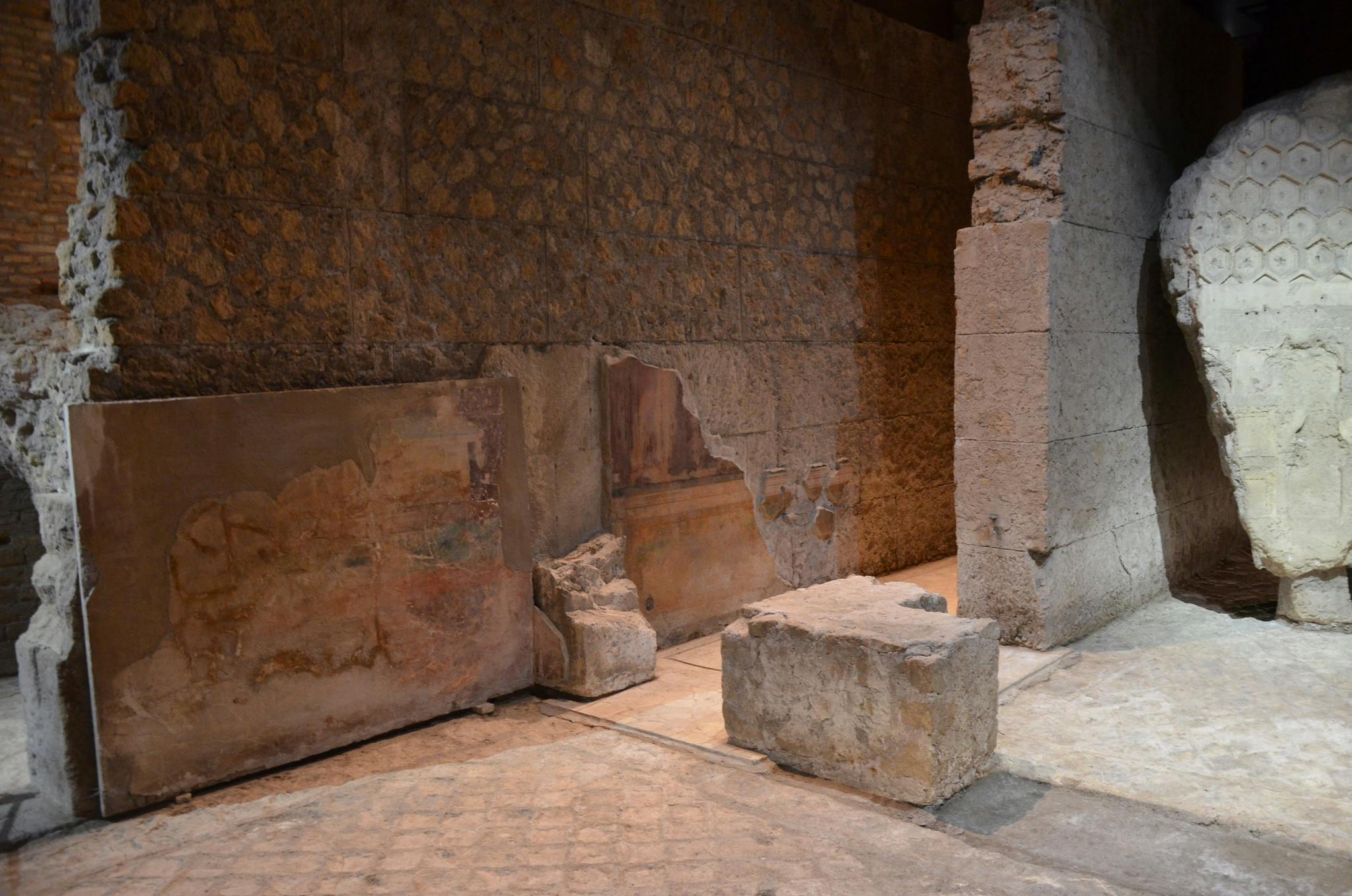 Parets antigues de pedra amb frescos parcialment conservats i grans blocs tallats en un jaciment arqueològic.