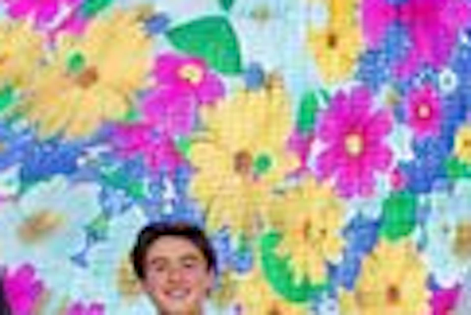 People standing and interacting in a mirrored room with colorful floral patterns covering the walls and reflections.
