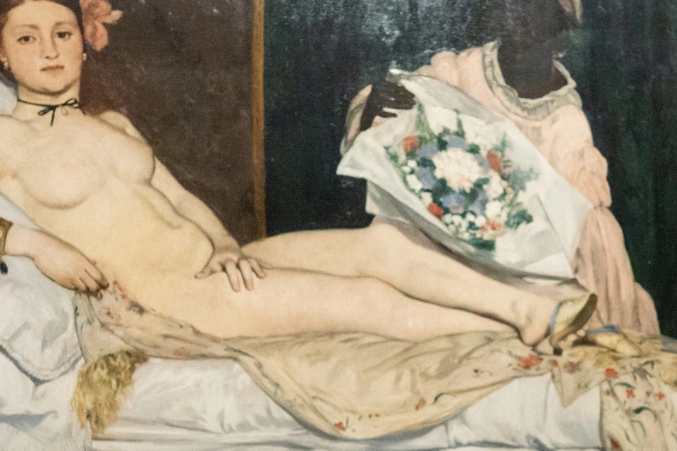 Two people discussing a famous painting of a reclining nude woman in a museum gallery with red walls.