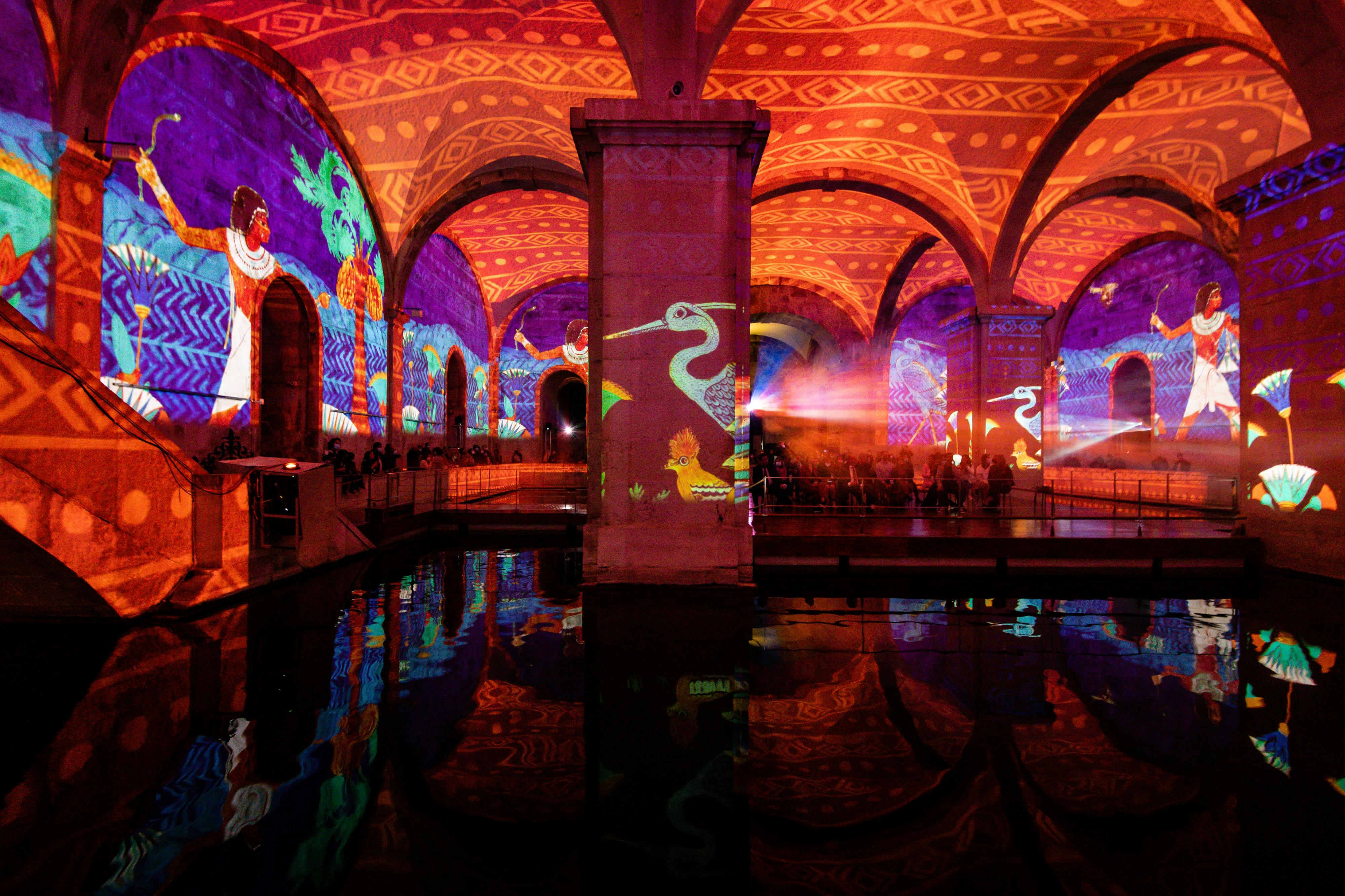 アーチ型の地下空間で、壁や天井にはカラフルなアニメーションが映し出され、下の水面に映し出されています。