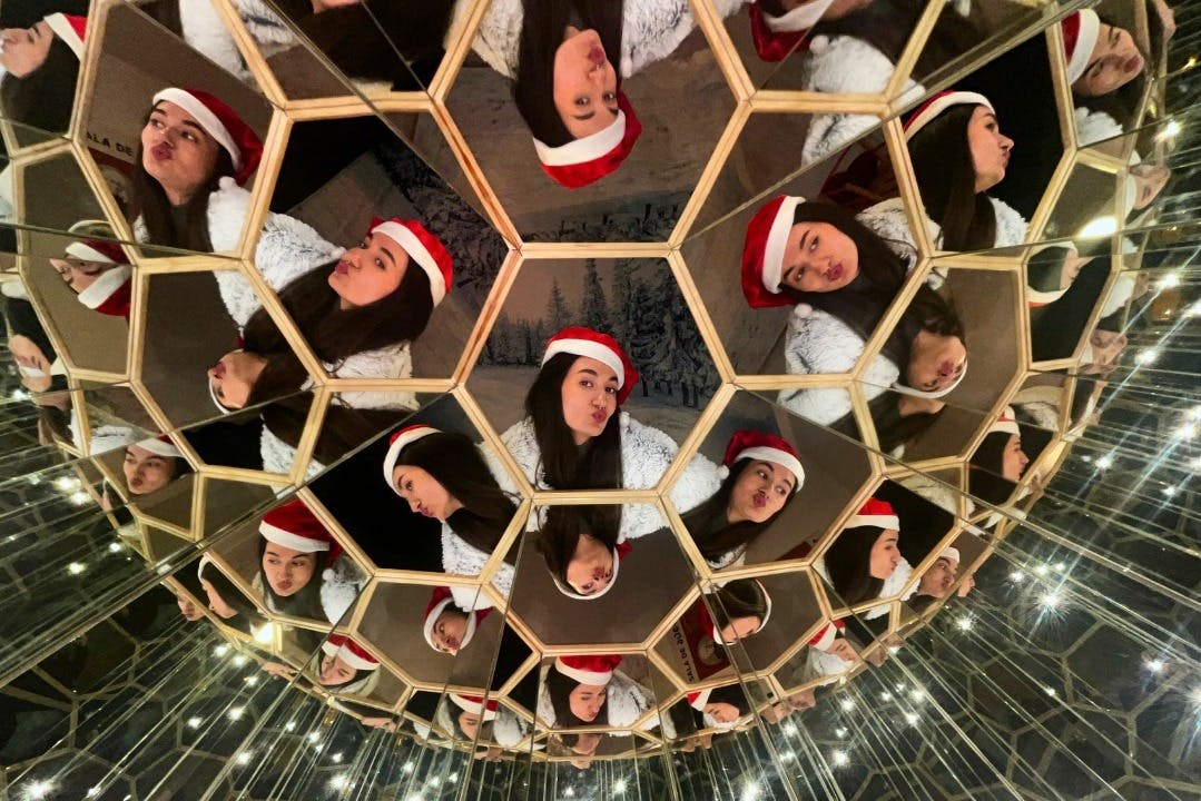 戴着圣诞老人帽子的人在几何镜子结构中多次反射，产生了万花筒效果。