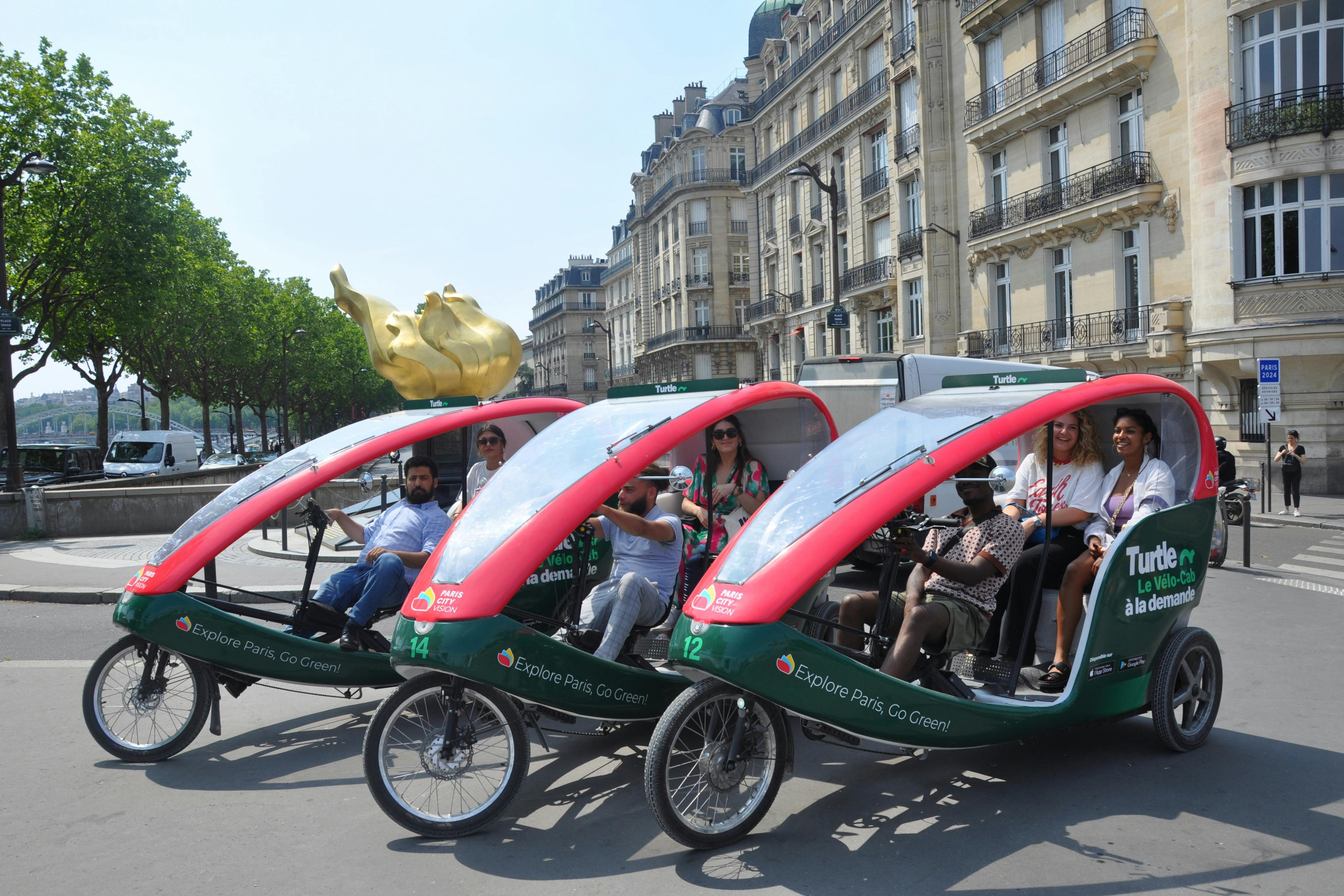 歴史的建造物に囲まれたパリの通りを乗客が走る3台の緑と赤のペディキャブ。