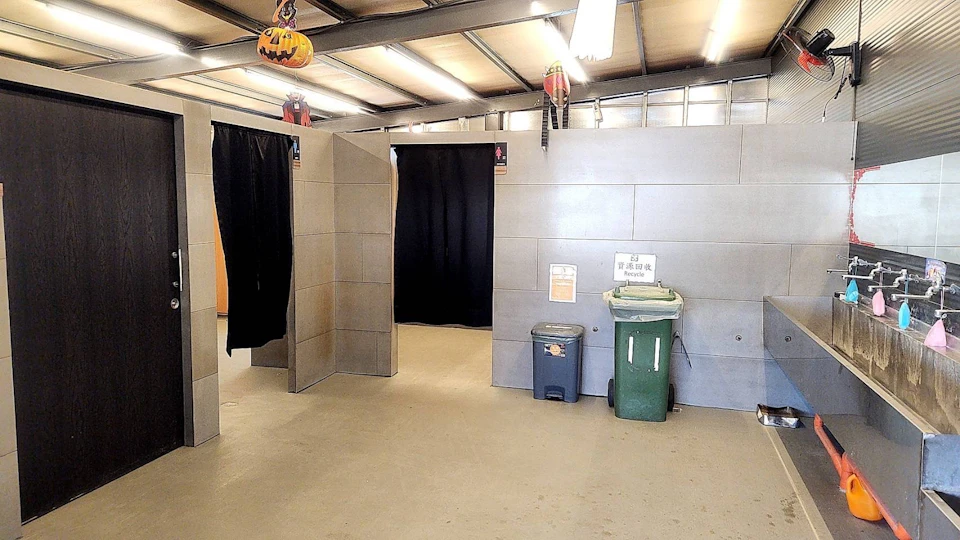 An indoor space with partitioned rooms, a trash bin, a recycling bin, and Halloween decorations hanging from the ceiling.