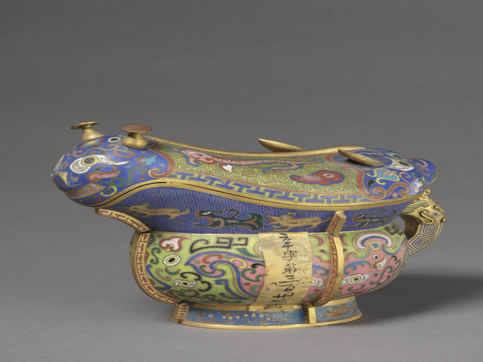 An ornate and colorful vessel with intricate patterns and a unique design, resembling an animal figure, on a gray background.