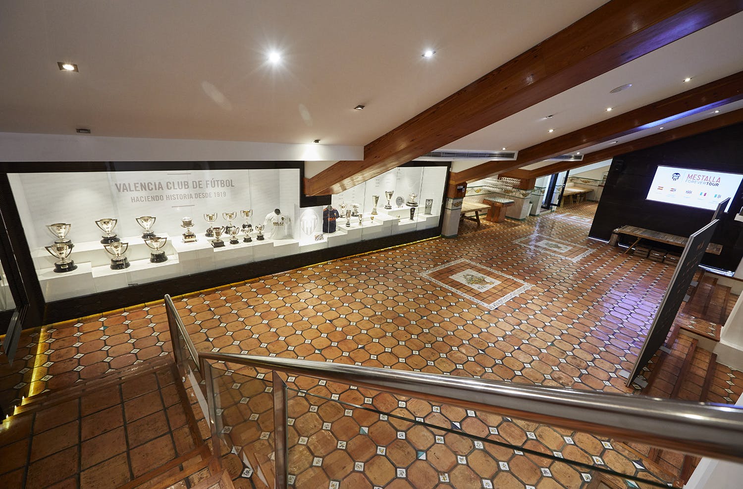 宽敞的房间，铺有瓷砖地板、木梁和陈列柜，展示了众多足球奖杯。