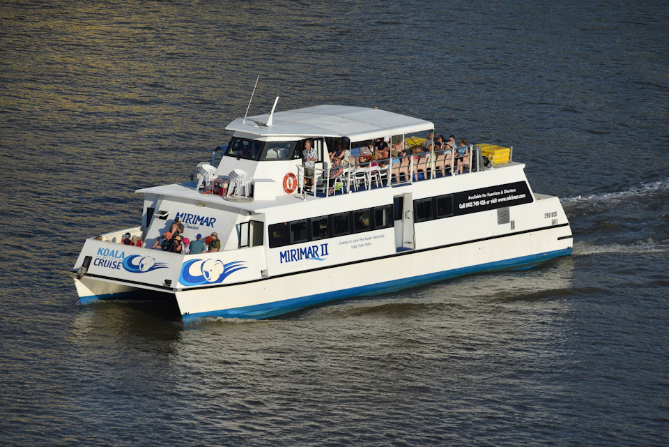 A white sightseeing boat named Mirimar II with passengers on multiple decks is cruising on a calm body of water.