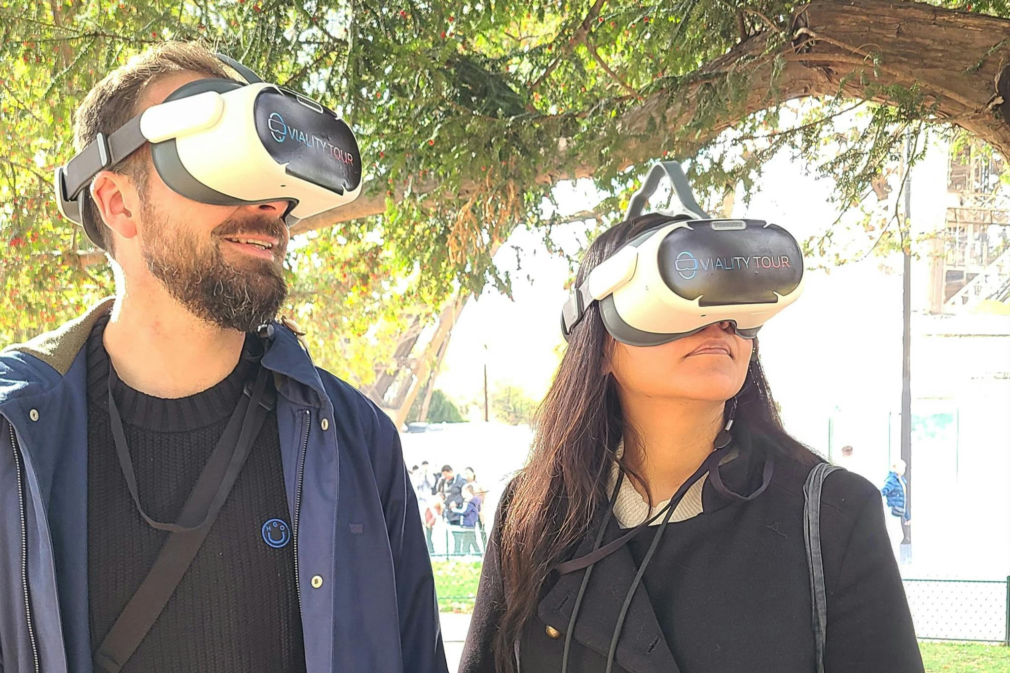 Due persone all'aperto che indossano cuffie per la realtà virtuale con alberi sullo sfondo.