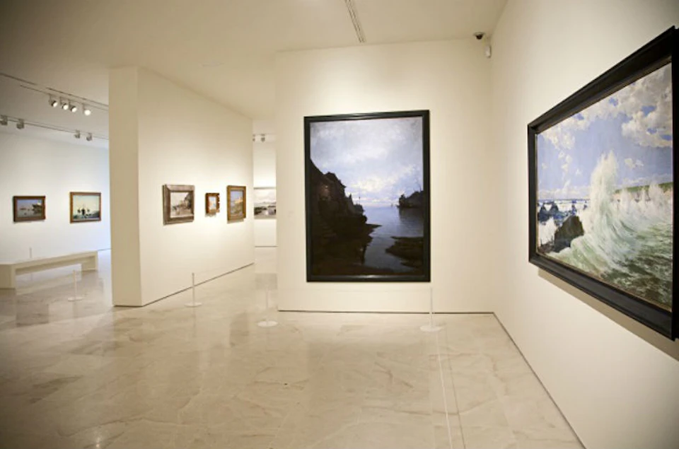 Art gallery with large landscape paintings on white walls and a polished marble floor. No people present.