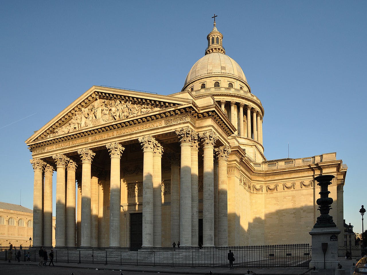 Neoclassical building with a large dome, Corinthian columns, and intricate pediment sculpture, set against a clear sky.