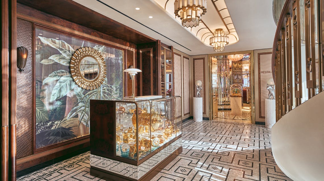 A luxurious interior with ornate decor, glass display case with gold items, patterned floor, and elegant light fixtures.
