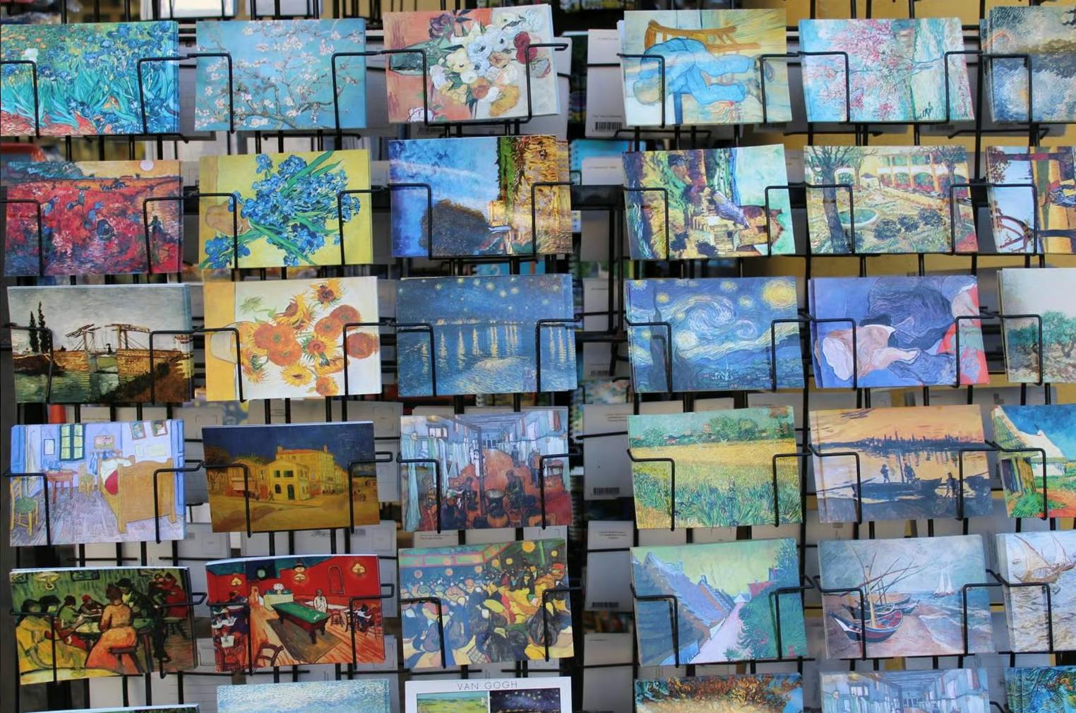 五颜六色的明信片陈列着文森特·梵高的著名画作，放在一个金属架子上。