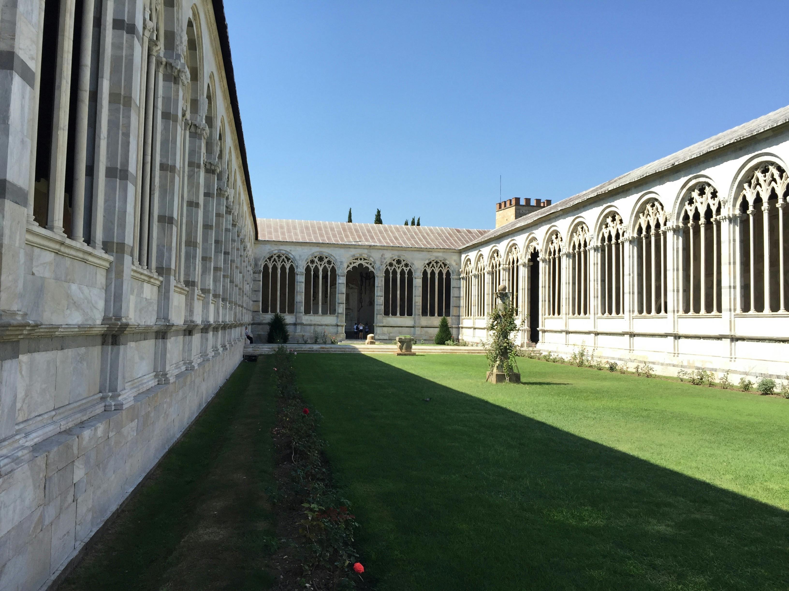 庭院里有修剪整齐的草地，晴朗的蓝天下有两个华丽的拱形柱廊。
