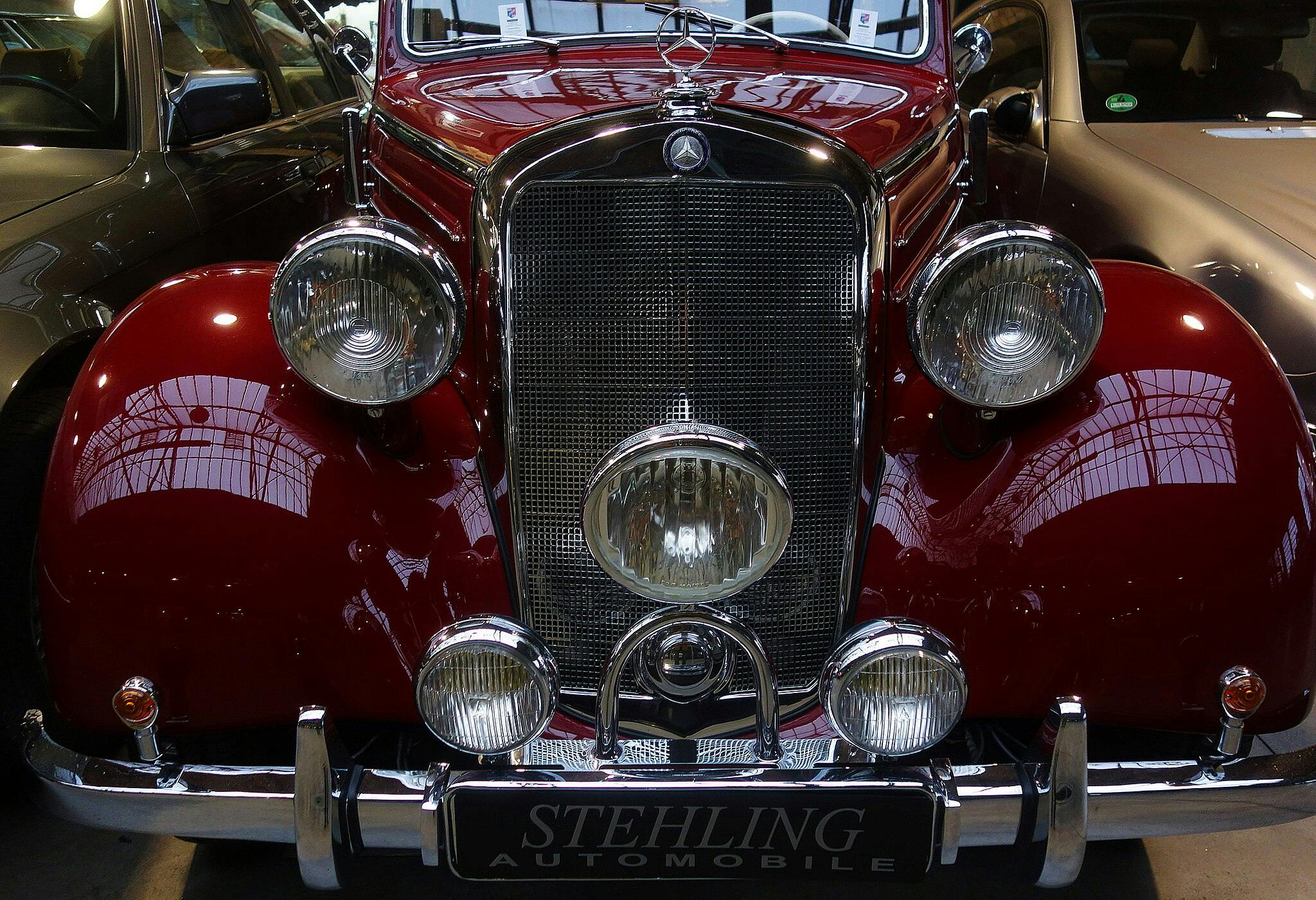 Front view of a vintage red automobile with a prominent chrome grille, multiple round headlights, and a "STEHLING AUTOMOBILE" logo.