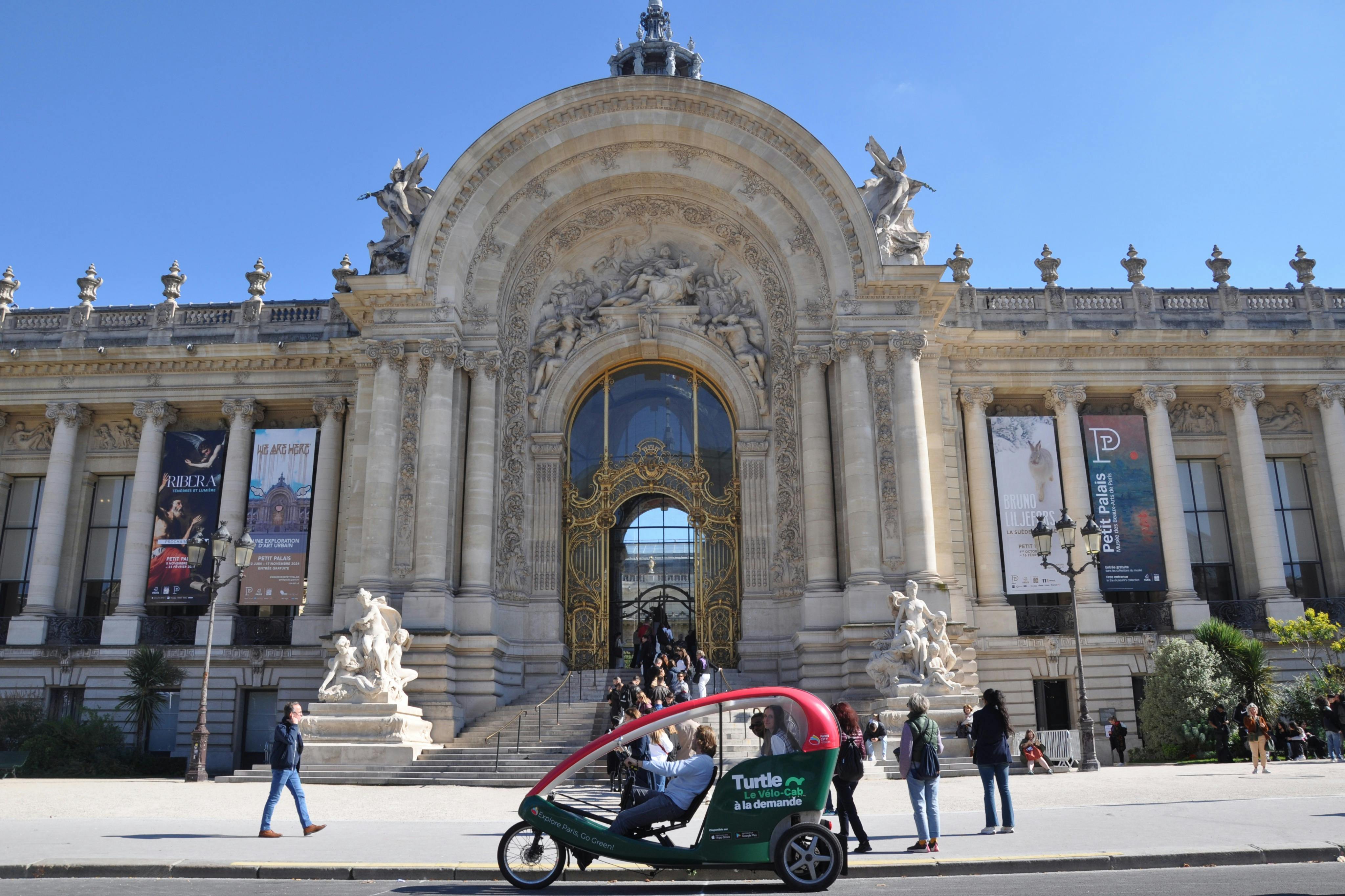 人々が歩き、赤緑色のペディキャブが入り口に彫像と大きなバナーがある壮大な建物の華やかなファサードを通り過ぎます。