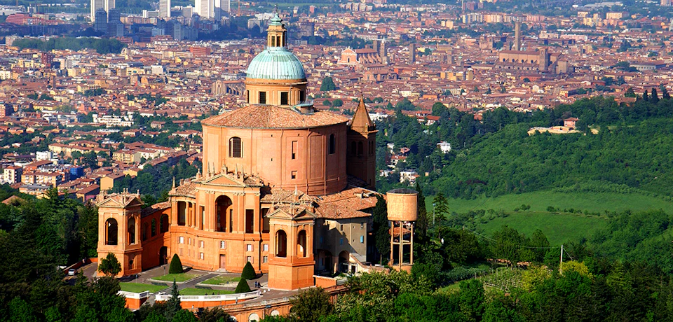 A large, historic building with a dome, surrounded by greenery, overlooking a dense cityscape with numerous buildings and trees.