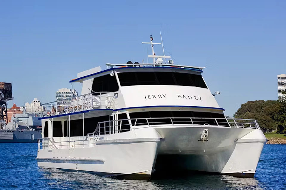 A large, white passenger boat named "Jerry Bailey" is docked in the water under a clear blue sky.