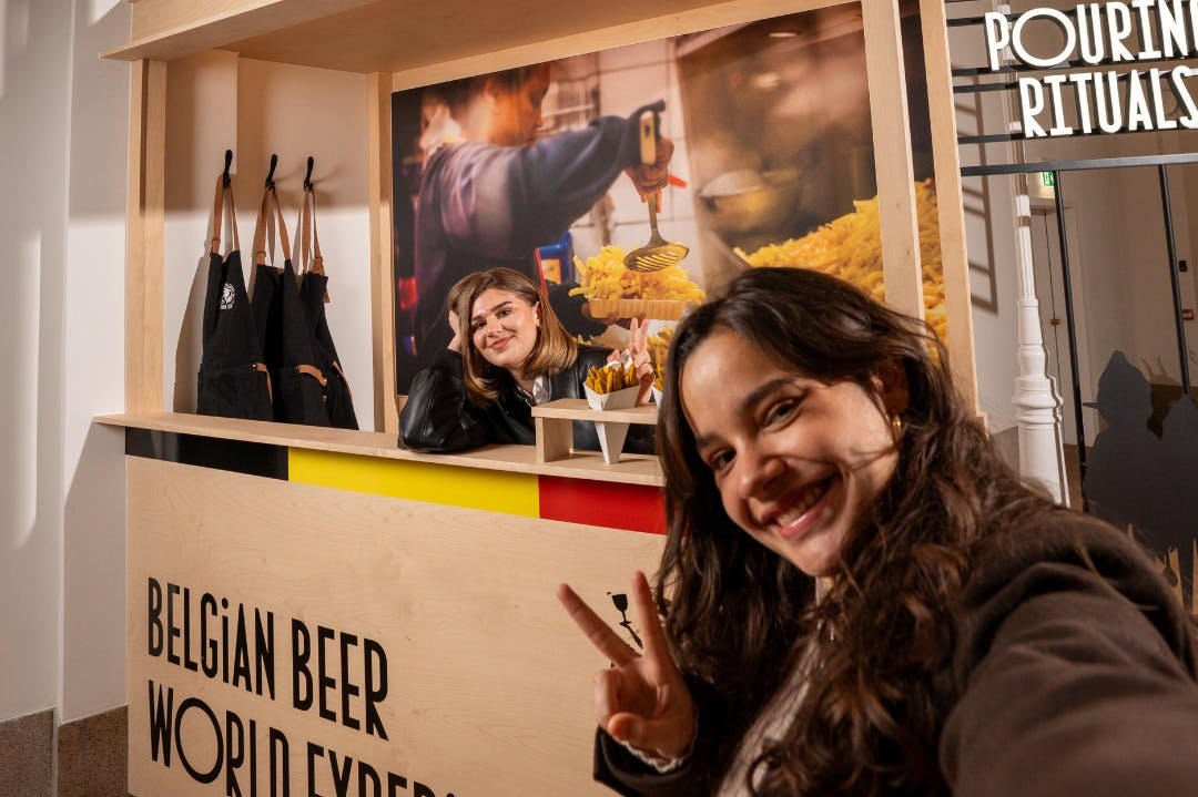 フライドポテトと鮮やかな背景を持つ屋台で、自撮りのために笑顔を浮かべている2人の女性。