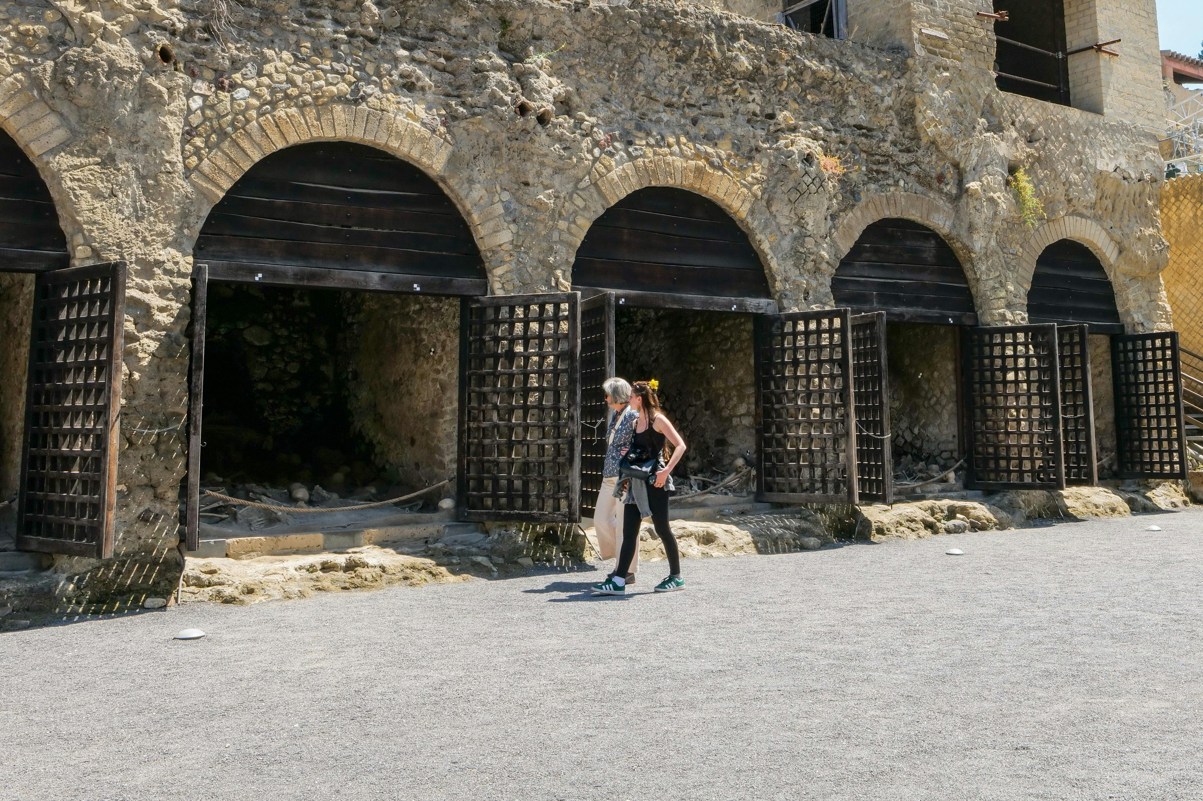 天気のいい日には、木製の門がある古代の石造りのアーチの前を2人が歩きます。