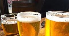 Dos vasos de cerveza con espuma sobre una mesa, con fondo borroso.