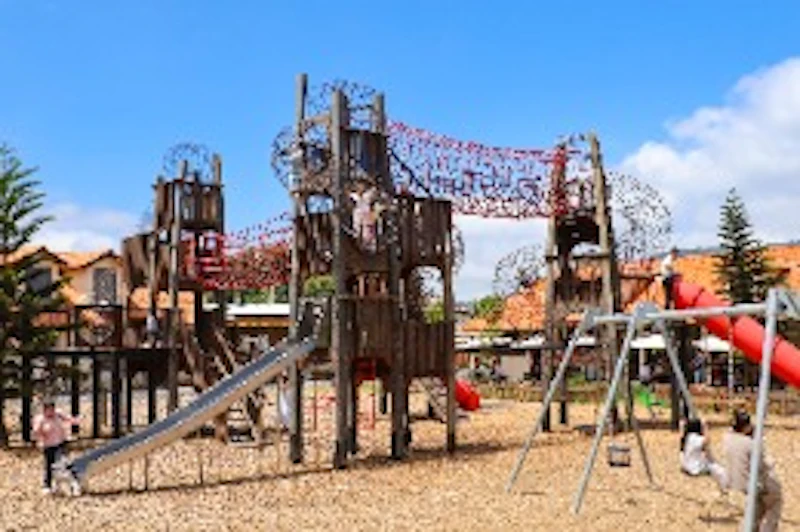 A playground featuring climbing structures, slides, and swings under a clear blue sky.