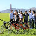 A group of friends pose in front of the bridge with their bikes