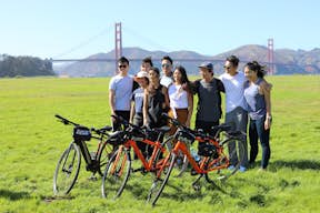 Een groep vrienden poseert voor de brug met hun fietsen