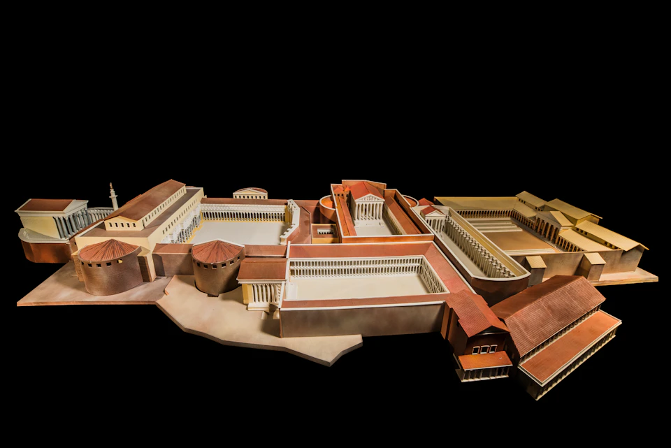 Model of an ancient architectural complex with multiple buildings, courtyards, and red-tiled roofs, set against a black background.