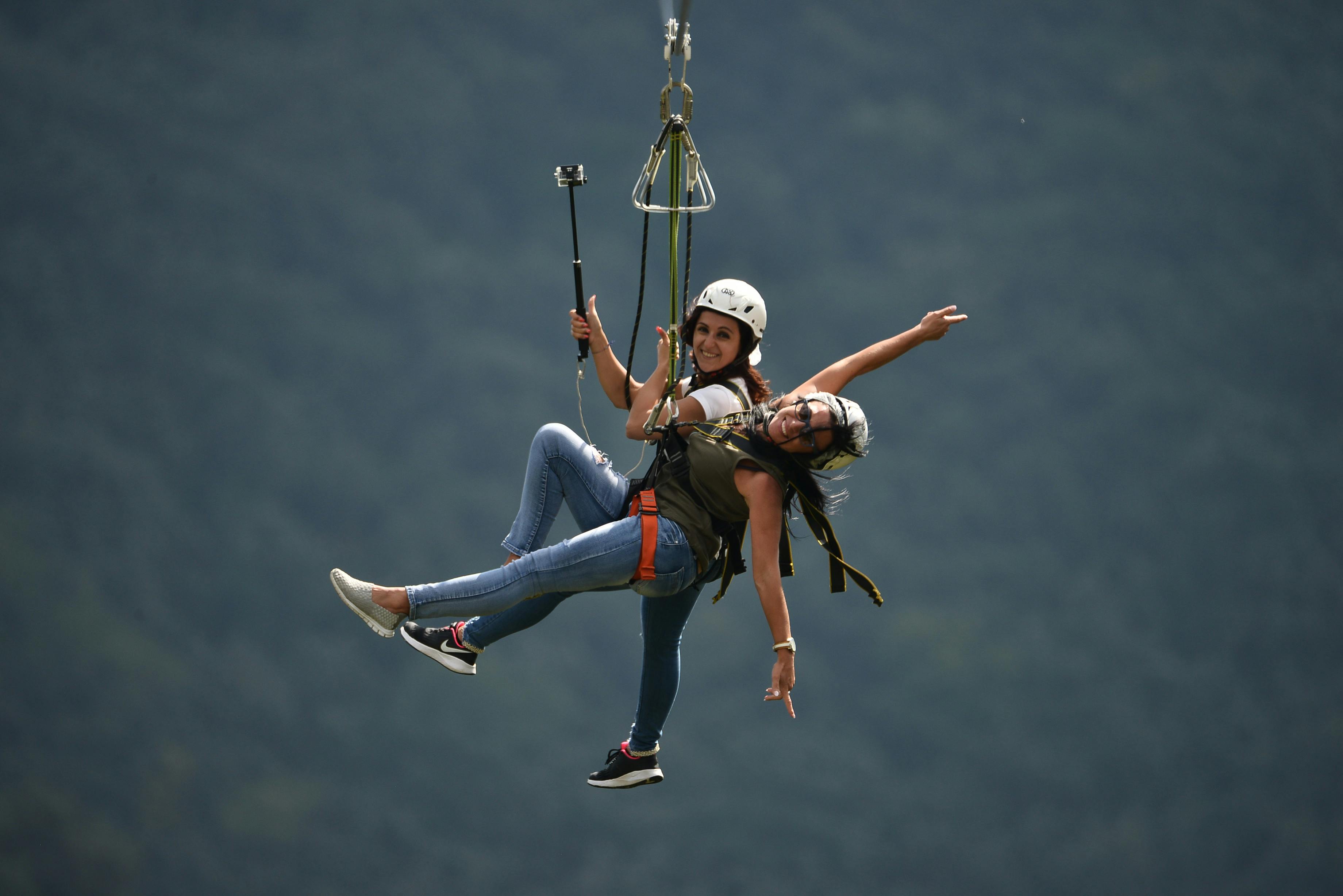 两个人都穿着头盔、马具和休闲服装，手里拿着自拍杆。