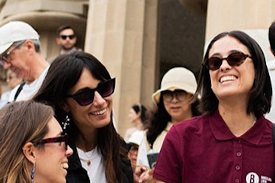 A group of people smiling and conversing on decorative stairs near columns and ornate structures in an outdoor setting.