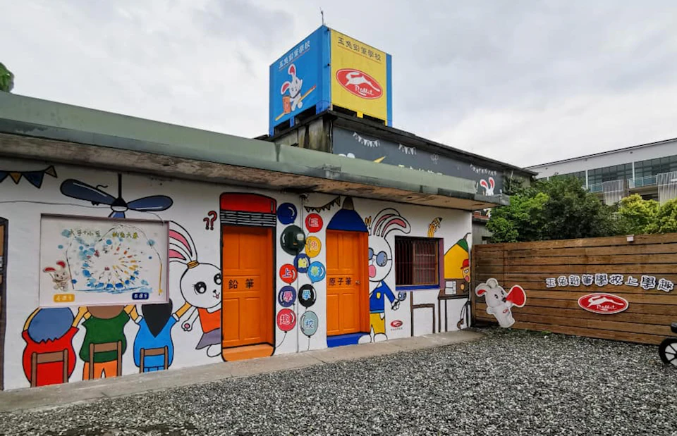A colorful building with cartoon rabbit murals and two orange doors under a cloudy sky.
