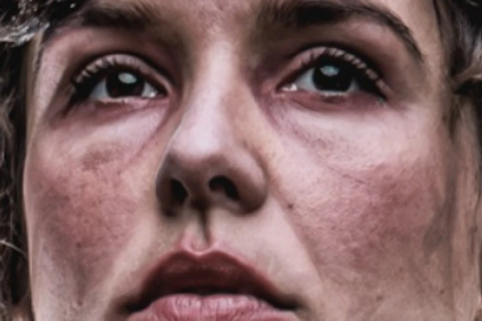 A woman in period clothing and a bonnet stands in front of a man in a suit, with dimly lit surroundings.