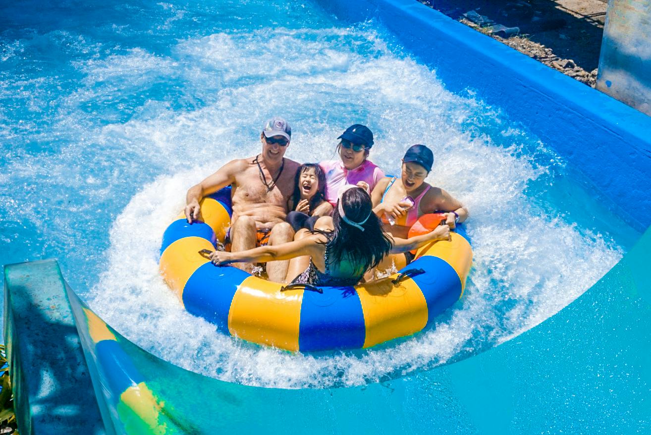 A group of people enjoying a ride on a circular inflatable raft in a water park.