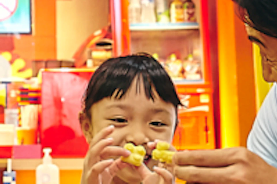 A family of four is eating at a vibrant LEGO-themed restaurant with red and white striped decor. They have LEGO-shaped dishes.