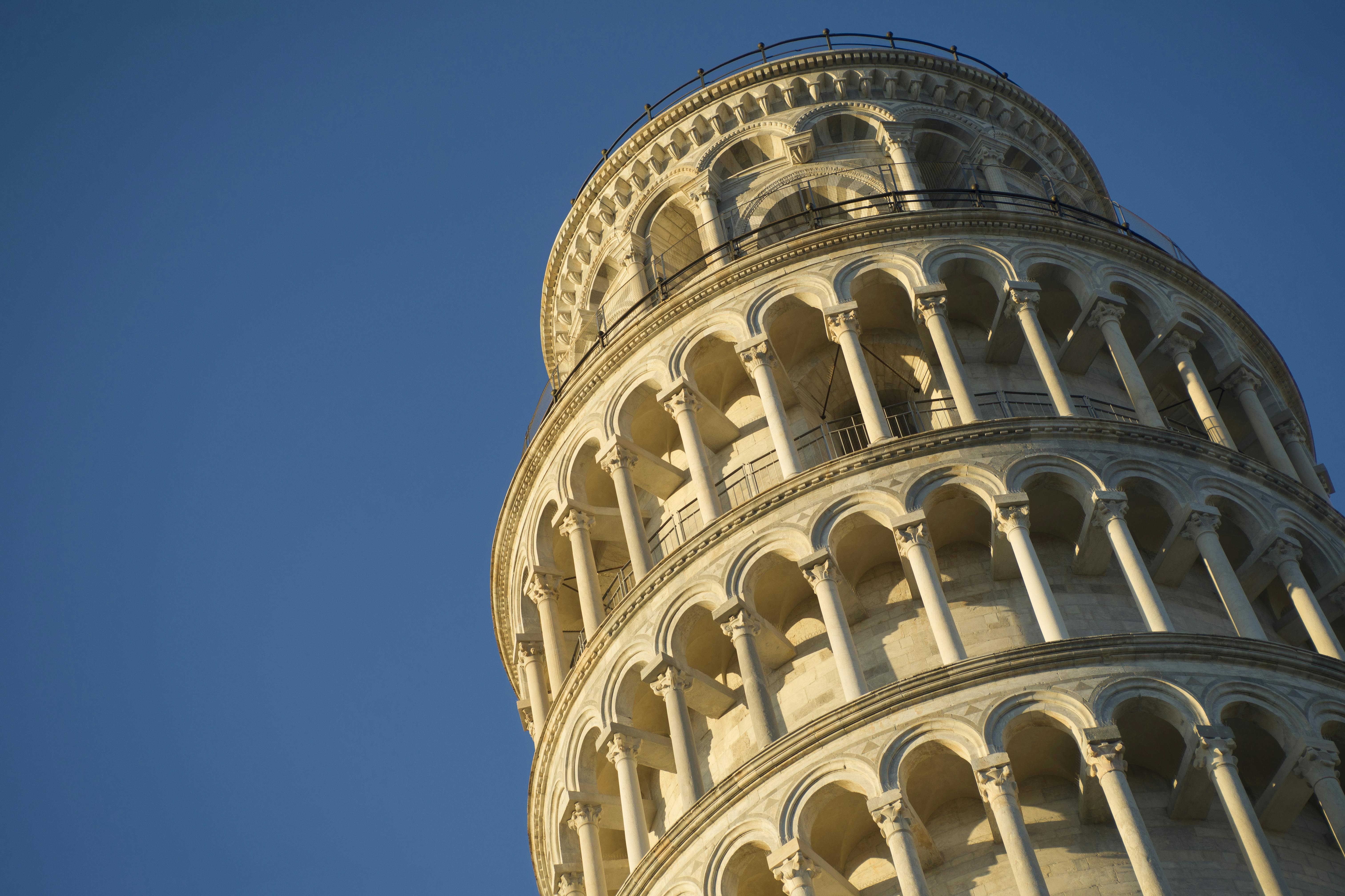Close-up of the upper portion of the Leaning Tower of Pisa against a clear blue sky.