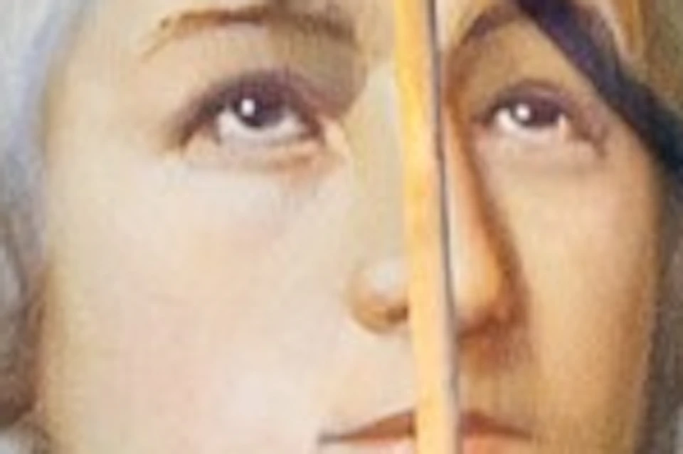 A woman in an orange sweater looks at a framed portrait of a historical figure with red paint splattered on the face.