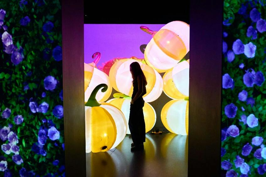 A person stands in a dimly lit room with illuminated pumpkin-shaped decorations in the background.
