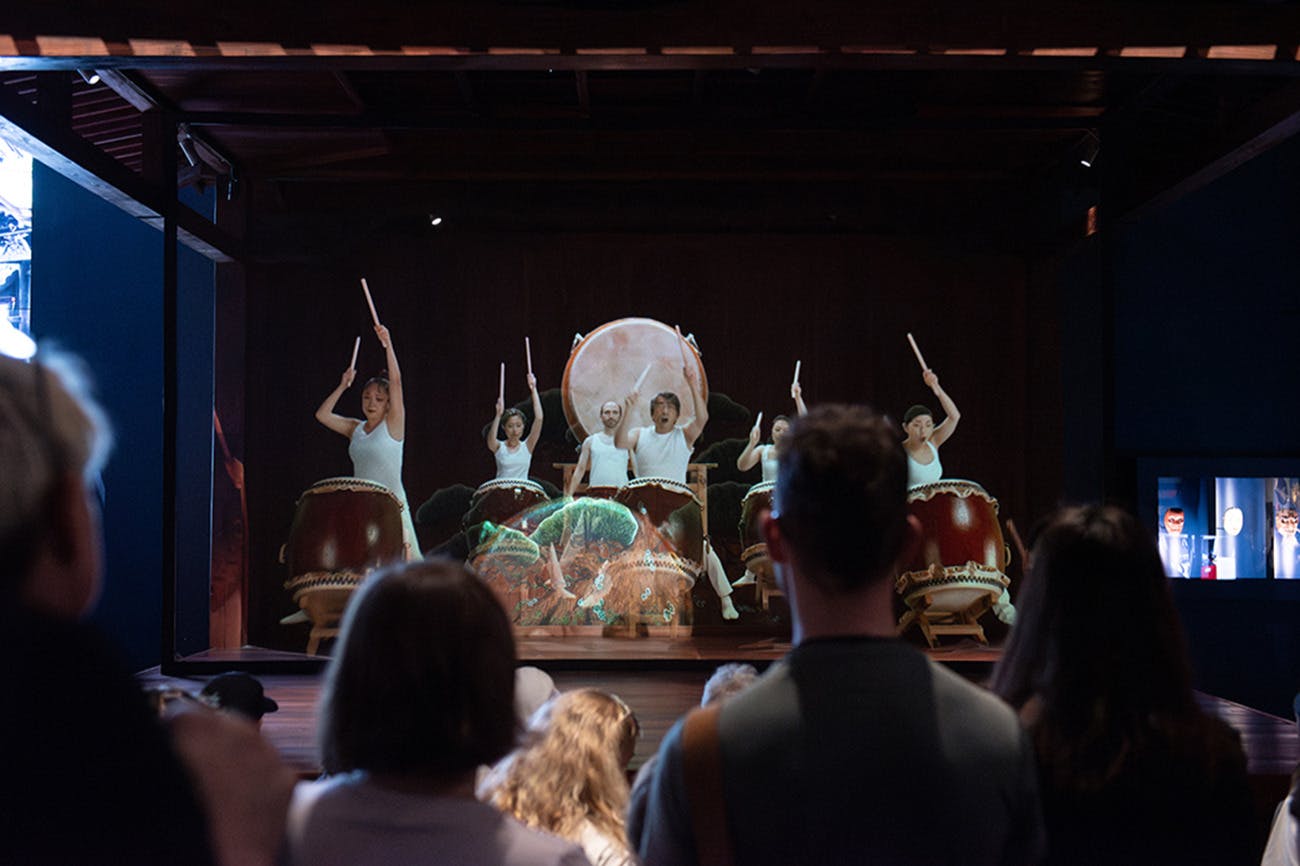 Un grup de bateristes actuant a l'escenari amb un públic mirant des del primer pla.