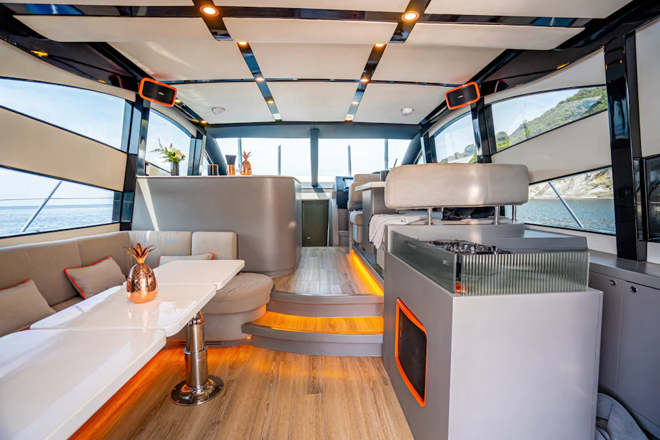 Luxurious boat interior featuring modern seating, a dining table, and elegant decor with soft lighting and large windows.