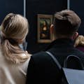 Um casal olha para a Mona Lisa de costas para a câmera
