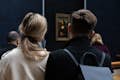 Een echtpaar kijkt naar de Mona Lisa met de rug naar de camera