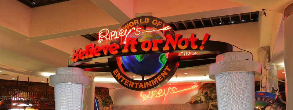 A neon-lit sign reading 'Ripley's Believe It or Not!' with a globe design at an indoor location.