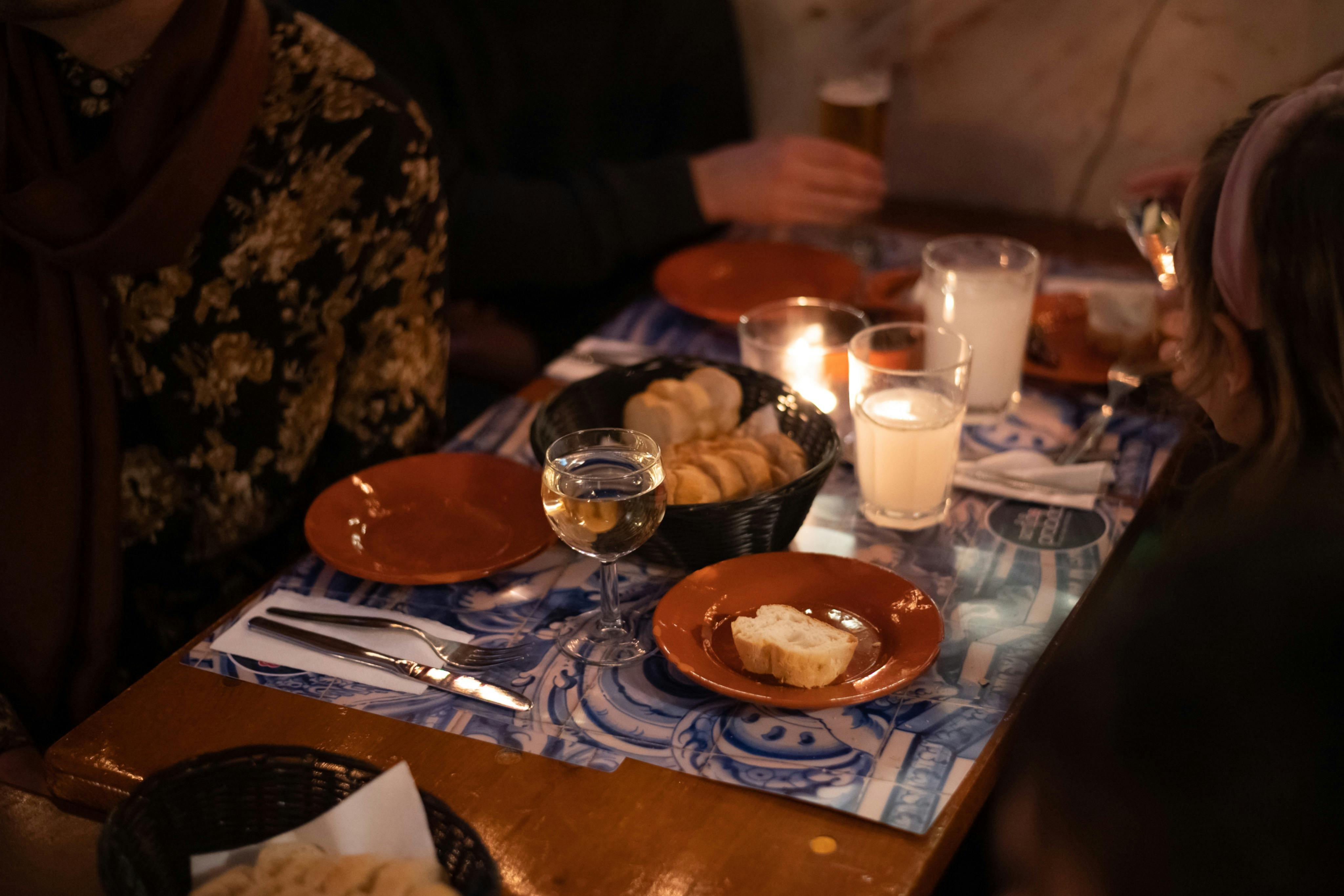 Tavolo a lume di candela con pane, bevande e un'accogliente atmosfera da pranzo
