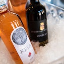 Two bottles of wine, one rosé and one red, chilling in a container filled with ice.
