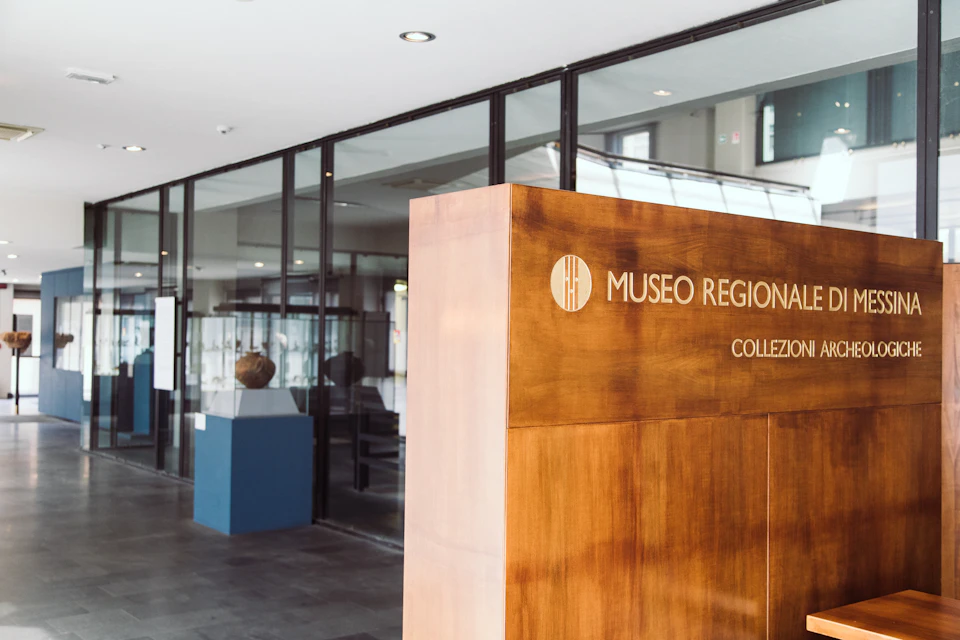 Interior of a museum with a wooden sign reading "Museo Regional" and glass display cases in the background.