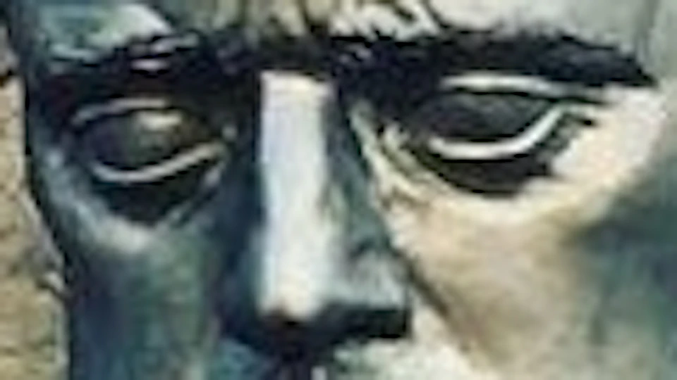 Metallic sculpture of a man's face with abstract shapes, placed on a stone platform with trees in the background.