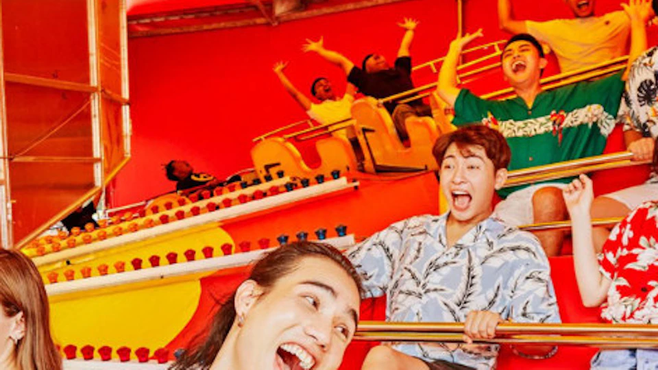 People enjoying a colorful amusement park ride under a bright, yellow canopy.