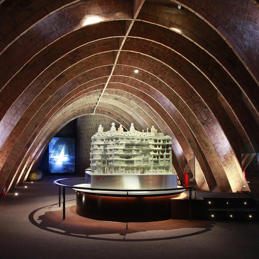 Pod klenutými cihlovými stropy je vystaven architektonický model budovy s bodovými světly osvětlujícími scénu.