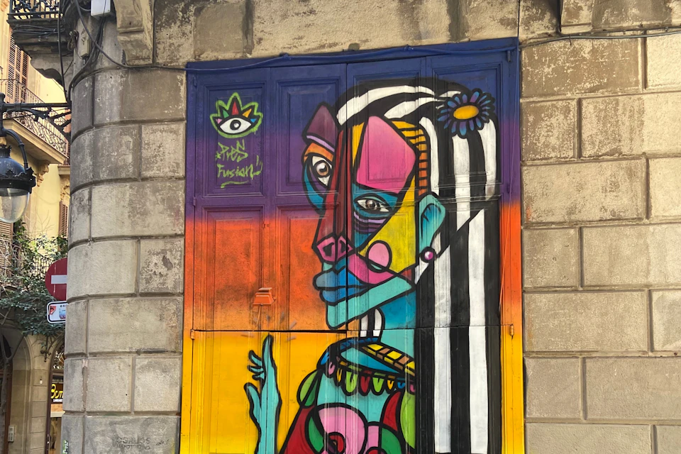 Picasso style cubist street art painted on the big wooden door of a 19th century building in Barcelona