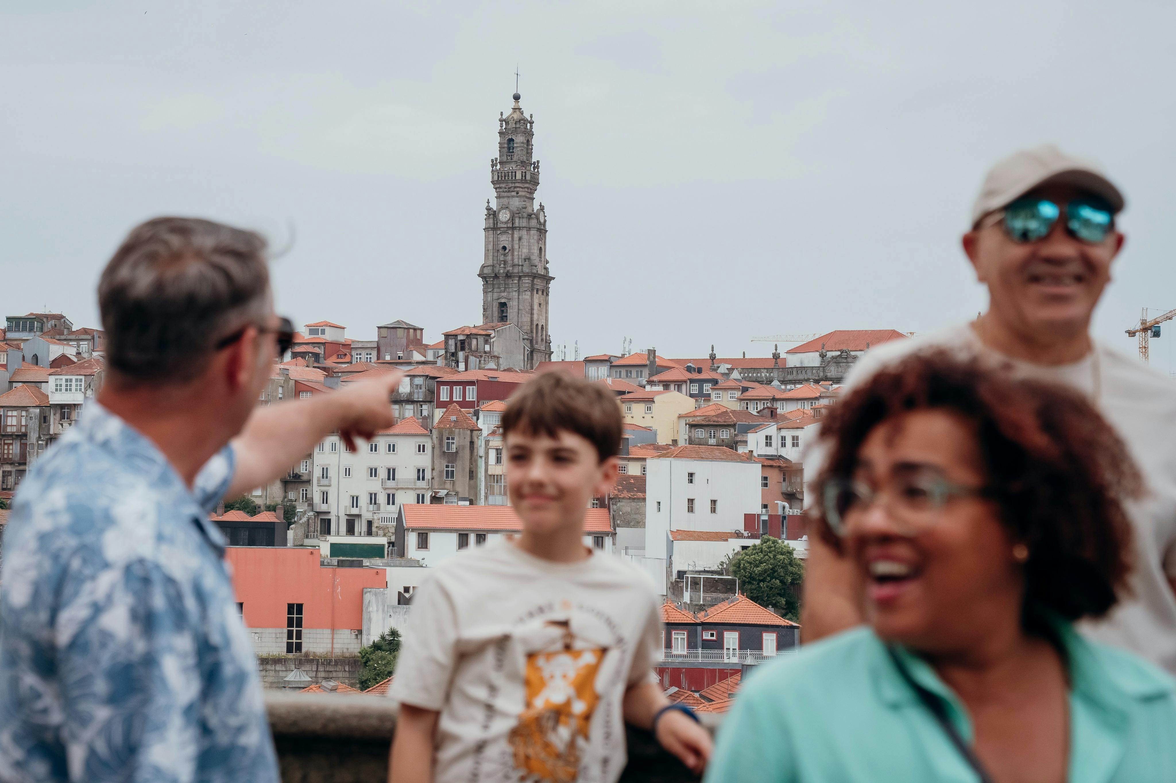 높은 시계탑을 배경으로 도시 풍경 앞에 서 있는 한 소년과 두 명의 어른이 미소를 짓고 있습니다.