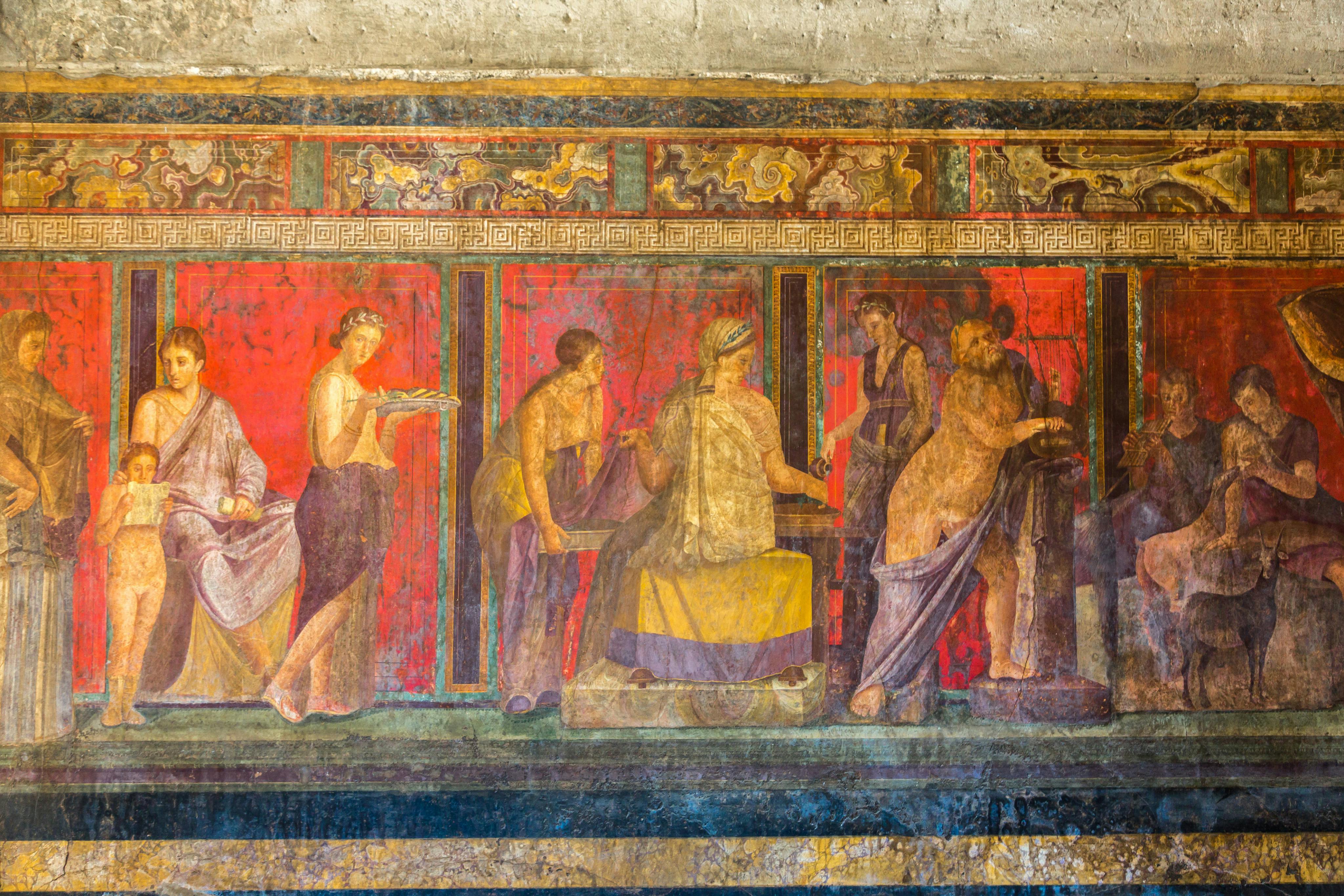Ancient fresco depicting several figures in colorful garments, engaging in various activities against a vibrant red background.